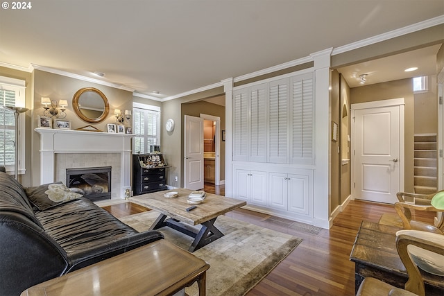 living room with a fireplace, crown molding, wood-type flooring, and a wealth of natural light