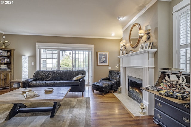 living room with a tiled fireplace, ornamental molding, and hardwood / wood-style flooring