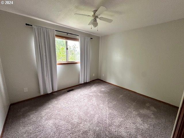 unfurnished room with carpet flooring and ceiling fan