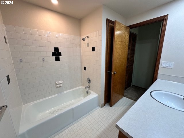 bathroom with tile patterned flooring, tiled shower / bath, and vanity