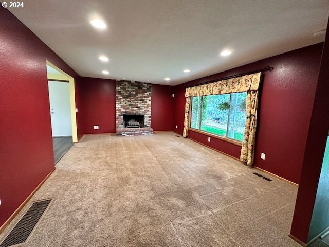 unfurnished living room with brick wall, a brick fireplace, and carpet floors