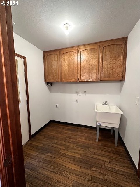 laundry room featuring a textured ceiling, cabinets, hookup for a washing machine, and dark hardwood / wood-style flooring