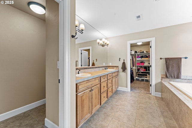 bathroom featuring tile patterned flooring, vanity, and tiled bath