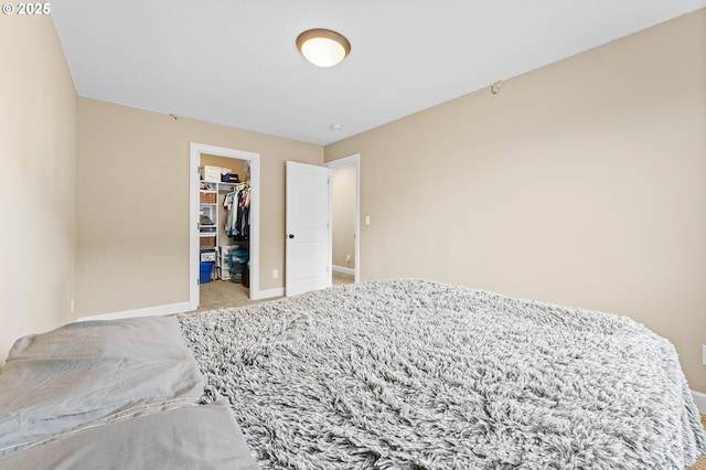 bedroom featuring a walk in closet, light colored carpet, and a closet