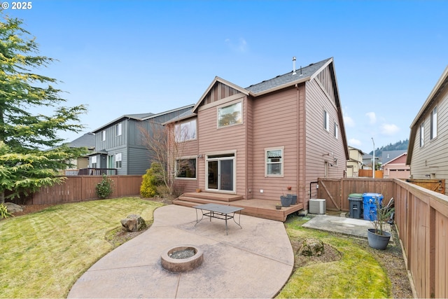 rear view of house with a wooden deck, a patio area, a lawn, and an outdoor fire pit