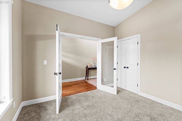 unfurnished bedroom featuring lofted ceiling, a closet, french doors, and carpet