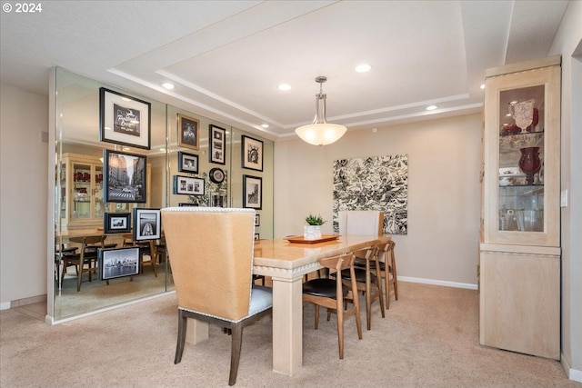 dining space featuring light colored carpet and a raised ceiling