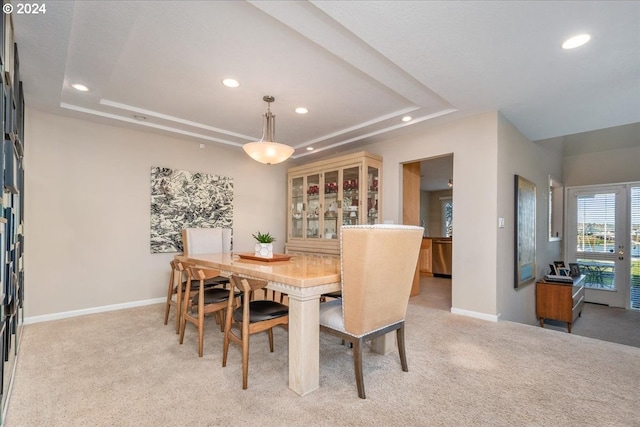 carpeted dining space featuring a tray ceiling