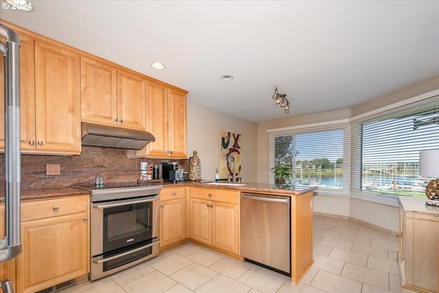 kitchen with backsplash, sink, light brown cabinetry, appliances with stainless steel finishes, and kitchen peninsula