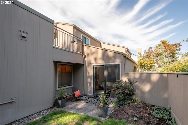 rear view of property featuring a balcony and a patio