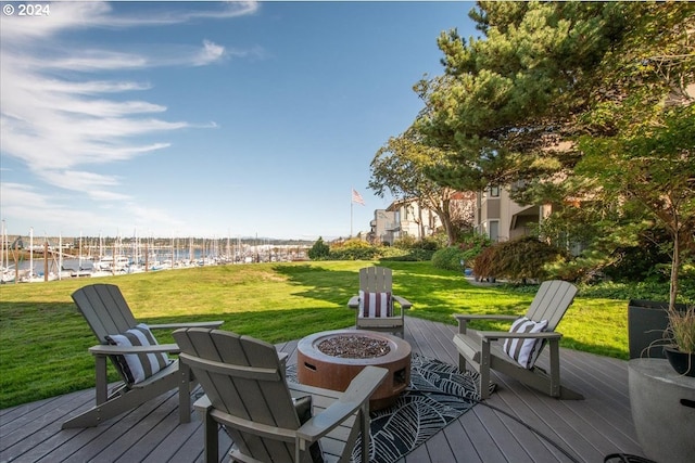 wooden terrace featuring a fire pit, a water view, and a yard