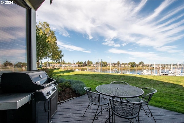 deck featuring a lawn, grilling area, and a water view