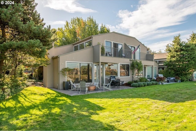 back of property featuring a lawn, a patio area, and a balcony