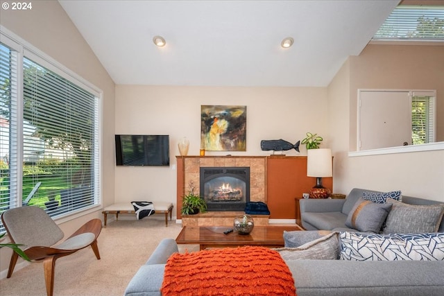 carpeted living room featuring vaulted ceiling and a tiled fireplace