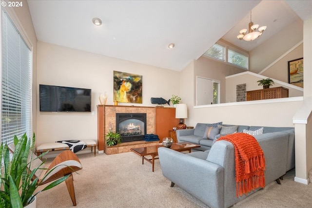 living room with light carpet, an inviting chandelier, vaulted ceiling, and a tiled fireplace