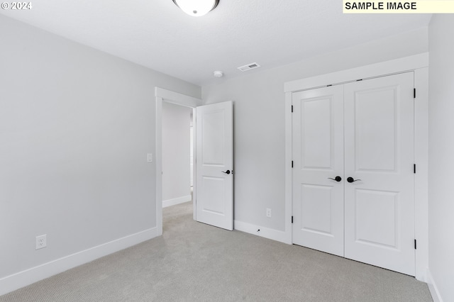 unfurnished bedroom featuring light carpet and a closet