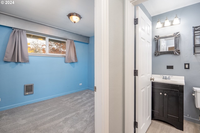 bathroom featuring vanity, heating unit, and toilet