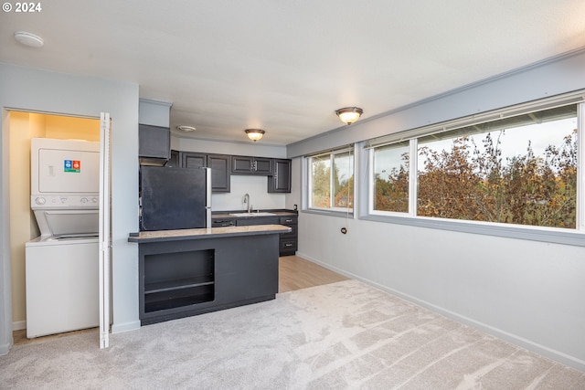 kitchen with gray cabinetry, sink, stacked washer and dryer, fridge, and light carpet