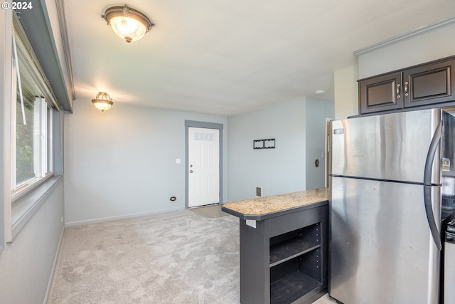 kitchen featuring stainless steel fridge, light colored carpet, dark brown cabinetry, and kitchen peninsula