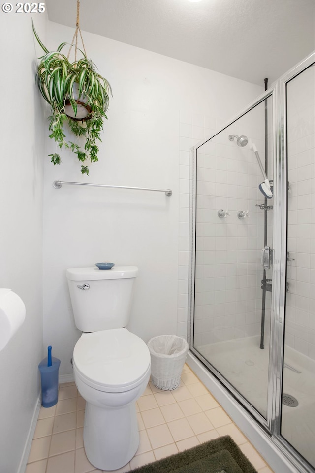 bathroom featuring toilet, tile patterned floors, and an enclosed shower