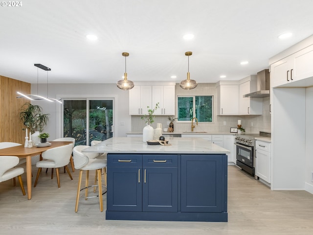 kitchen with wall chimney range hood, white cabinetry, hanging light fixtures, and electric stove