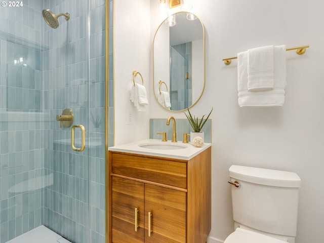 bathroom featuring a shower with door, vanity, and toilet