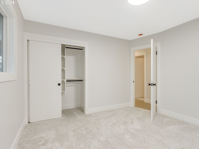 unfurnished bedroom featuring a closet and light carpet