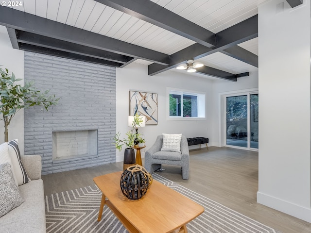 living room featuring beam ceiling, wood-type flooring, and a fireplace