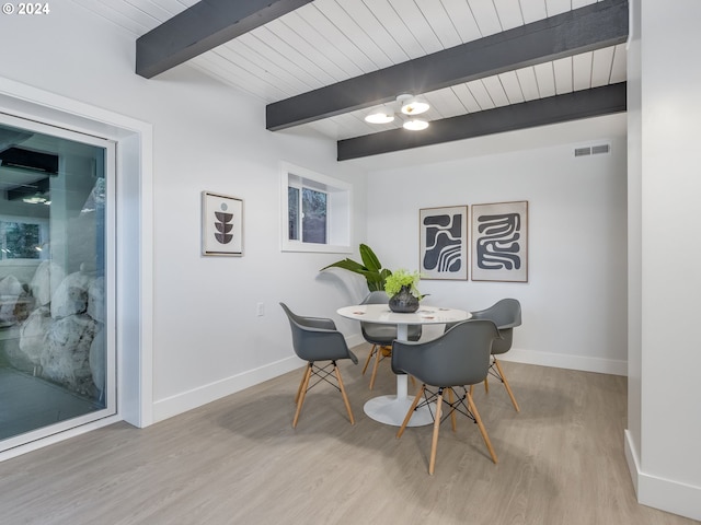 dining area with light hardwood / wood-style flooring, beamed ceiling, and wooden ceiling