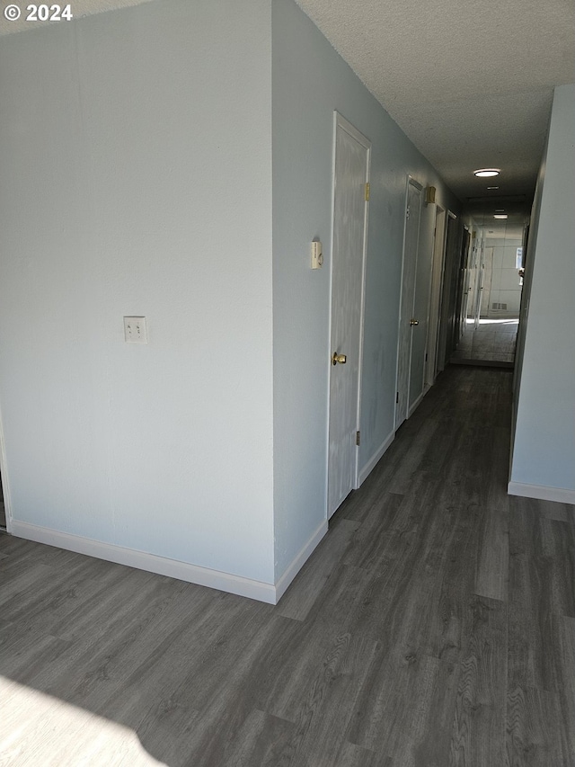 hallway featuring dark wood-type flooring and a textured ceiling