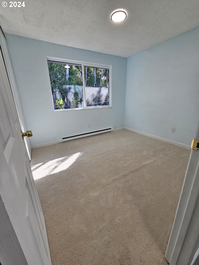 carpeted empty room featuring a textured ceiling and a baseboard heating unit