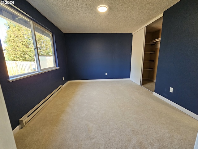 unfurnished bedroom with a closet, a textured ceiling, baseboard heating, and carpet floors