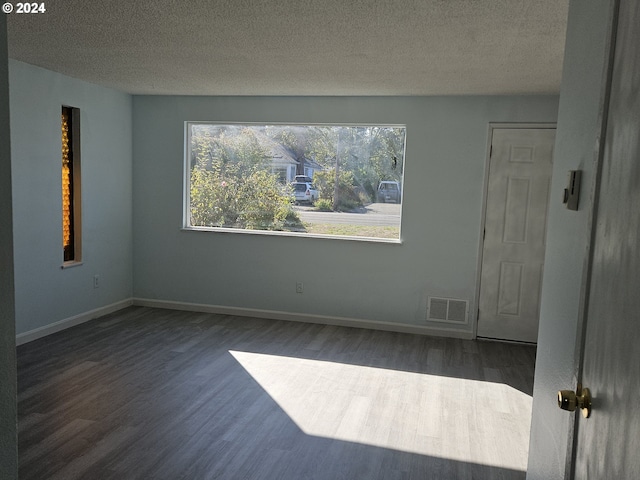 empty room with dark hardwood / wood-style floors and a textured ceiling