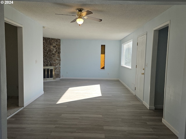 unfurnished living room featuring a textured ceiling, a fireplace, dark hardwood / wood-style flooring, and ceiling fan