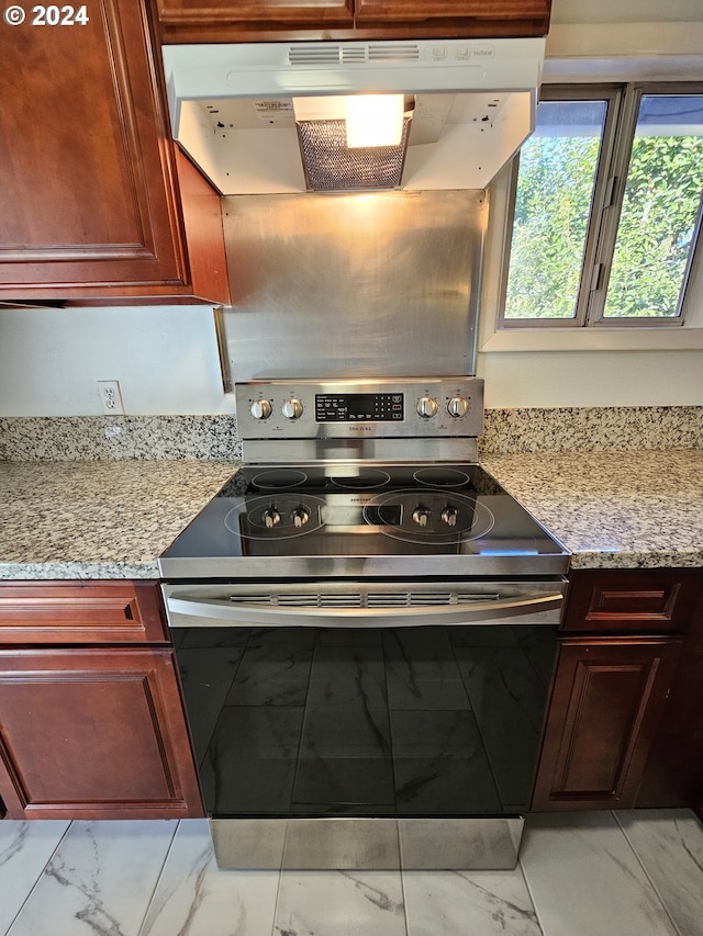 kitchen with light stone countertops and stainless steel electric stove