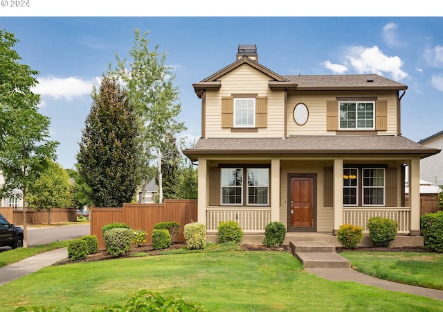 traditional home with covered porch, a chimney, a front lawn, and fence