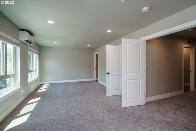 unfurnished room featuring a wall unit AC and carpet flooring