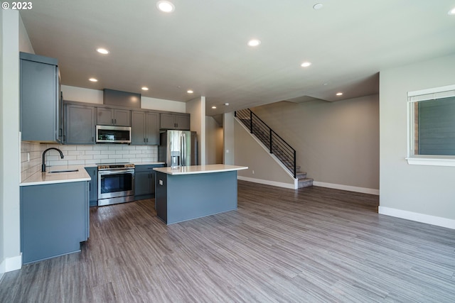 kitchen with backsplash, dishwasher, hardwood / wood-style flooring, sink, and a center island