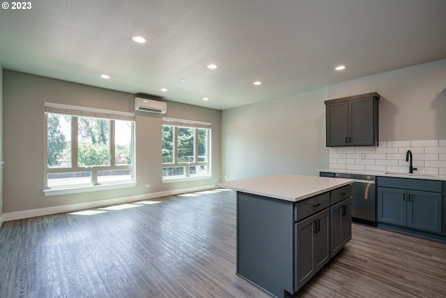 kitchen with appliances with stainless steel finishes, a kitchen island, backsplash, hardwood / wood-style flooring, and sink