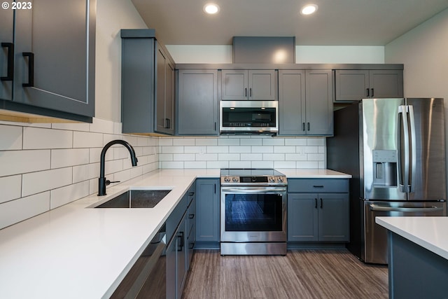 kitchen featuring light wood-type flooring, gray cabinets, backsplash, stainless steel appliances, and sink