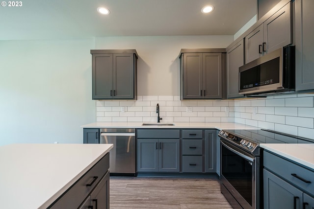 kitchen with a center island, wood-type flooring, backsplash, stainless steel appliances, and sink