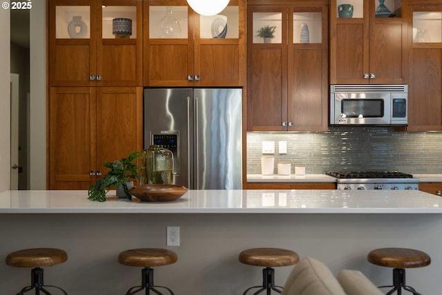 820 NW 12th Ave Unit 110, Portland, OR 97209 - kitchen featuring stainless steel appliances, light countertops, backsplash, and brown cabinets