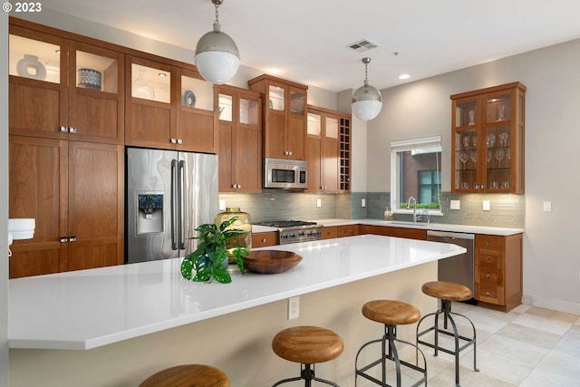 kitchen with pendant lighting, sink, stainless steel appliances, a breakfast bar, and decorative backsplash