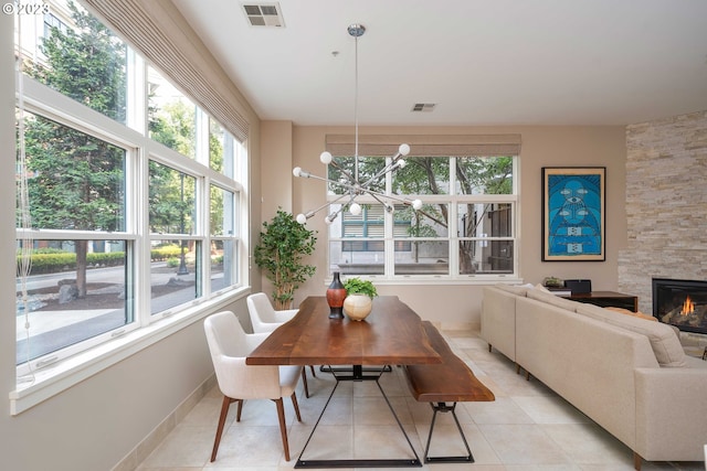 dining area with a notable chandelier, a fireplace, light tile patterned flooring, and a wealth of natural light