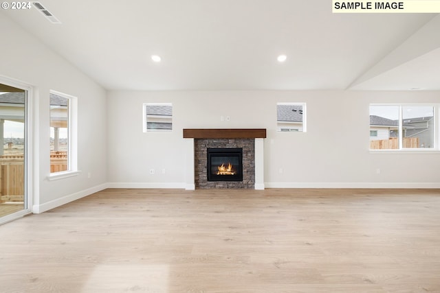 unfurnished living room with a stone fireplace and light hardwood / wood-style floors