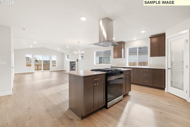 kitchen with vaulted ceiling, a kitchen island, island exhaust hood, gas range oven, and light hardwood / wood-style flooring