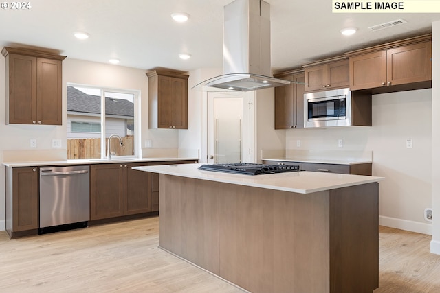 kitchen with appliances with stainless steel finishes, light hardwood / wood-style floors, a kitchen island, and island range hood