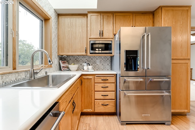 kitchen with decorative backsplash, light hardwood / wood-style floors, sink, and stainless steel appliances