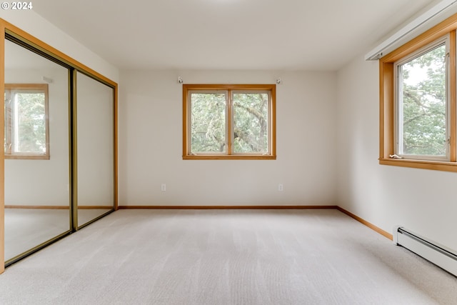 unfurnished bedroom with light carpet, a baseboard heating unit, and a closet