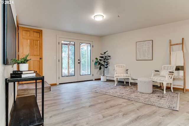 sitting room featuring light wood-type flooring, baseboard heating, and french doors